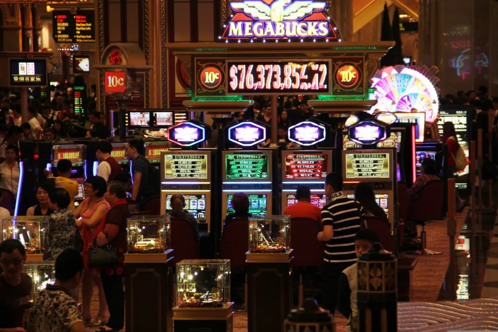 Photo de l'intérieur d'un casino avec des gens installés sur des machines à sous.
