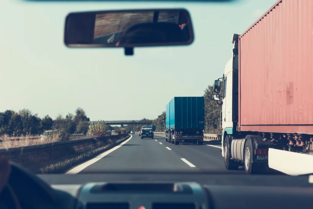 Une file de camions avec leurs remorques sur l'autoroute depuis l'habitacle d'une voiture.