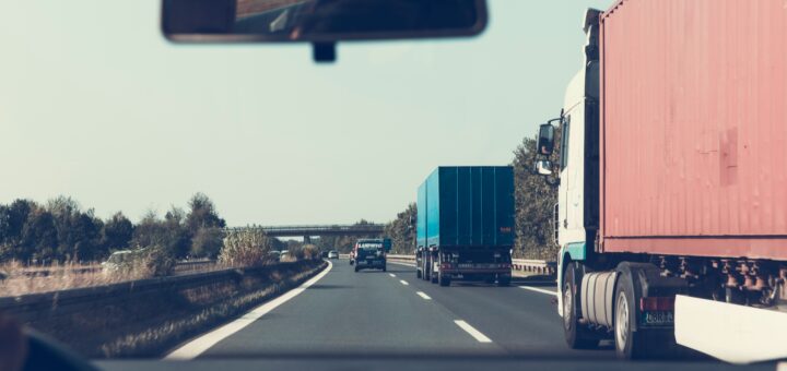 Une file de camions avec leurs remorques sur l'autoroute depuis l'habitacle d'une voiture.